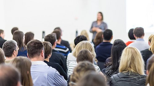 Foto, eine Gruppe von MEnschen verfolgt einen Vortrag