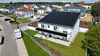 Foto, Mehrfamilienhaus aus der Vogelperspektive mit Photovoltaikmodulen auf dem Dach.