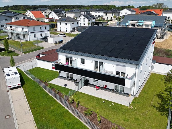 Foto, Mehrfamilienhaus aus der Vogelperspektive mit Photovoltaikmodulen auf dem Dach.