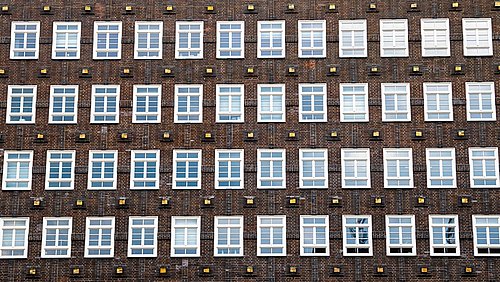 Foto, dunkelrote Ziegelfassade mit einer Vielzahl an Fenstern