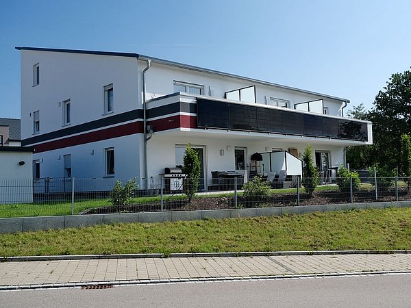 Foto, dreistöckiges Mehrfamilienhaus mit Terrassen.