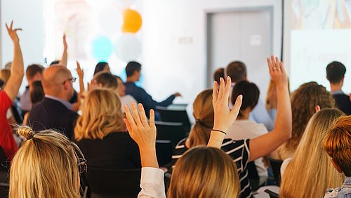 Foto, Menschen heben ihr Hand zur Abstimmung bei einer Veranstaltung