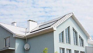 Foto, ein Wohnhaus mit weißem, hitzereduzierendem Dach und einer Solaranlage.