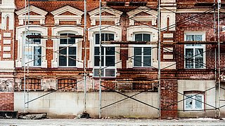 Foto, Baugerüst vor einem alten Gebäude mit roter Ziegelstein-Fassade,